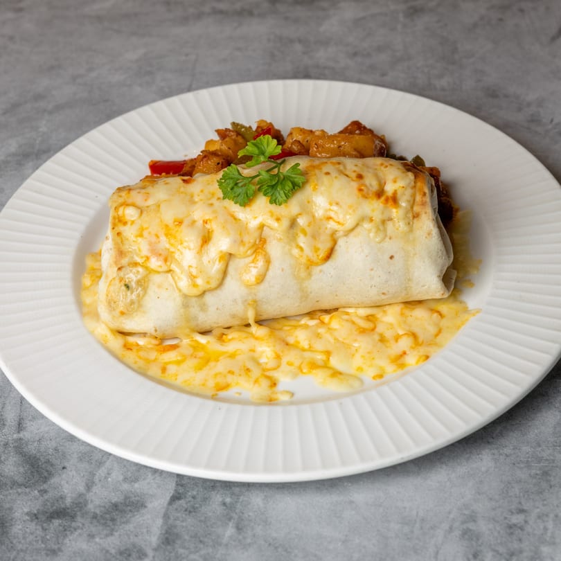 Cheesy burrito with melted cheese and a side of vegetables on a white plate.